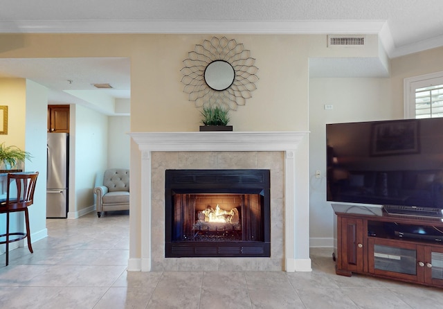 living room featuring crown molding, a fireplace, visible vents, and baseboards