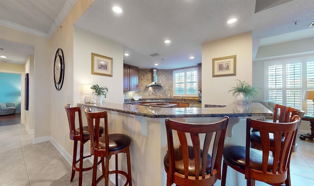 kitchen featuring light tile patterned floors, decorative backsplash, dark stone countertops, and a breakfast bar area