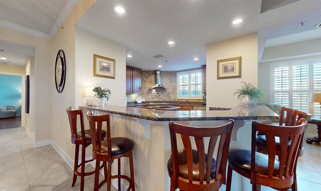 kitchen featuring backsplash, a breakfast bar, dark stone counters, light tile patterned floors, and recessed lighting