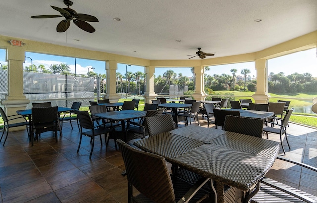 sunroom / solarium featuring a healthy amount of sunlight, a ceiling fan, and decorative columns