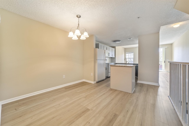 kitchen with freestanding refrigerator, a kitchen island, backsplash, and light wood finished floors
