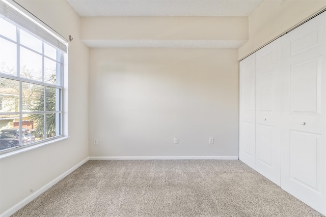 unfurnished bedroom with carpet floors, a closet, and baseboards