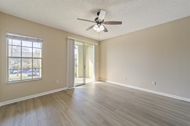 empty room with a ceiling fan, a textured ceiling, baseboards, and wood finished floors