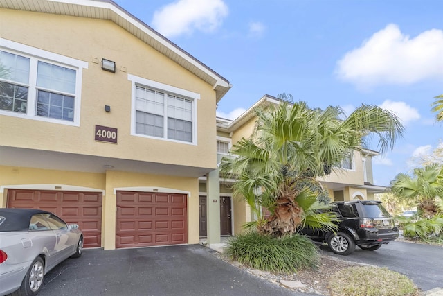 multi unit property with a garage, driveway, and stucco siding