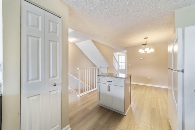 kitchen with a chandelier, freestanding refrigerator, decorative light fixtures, and light wood-style flooring