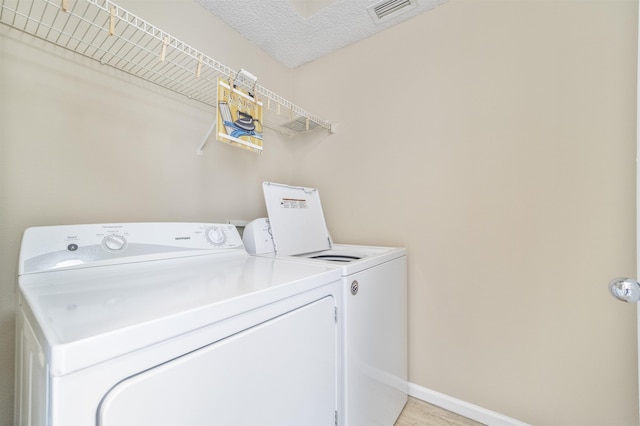 laundry room with visible vents, washing machine and dryer, a textured ceiling, laundry area, and baseboards
