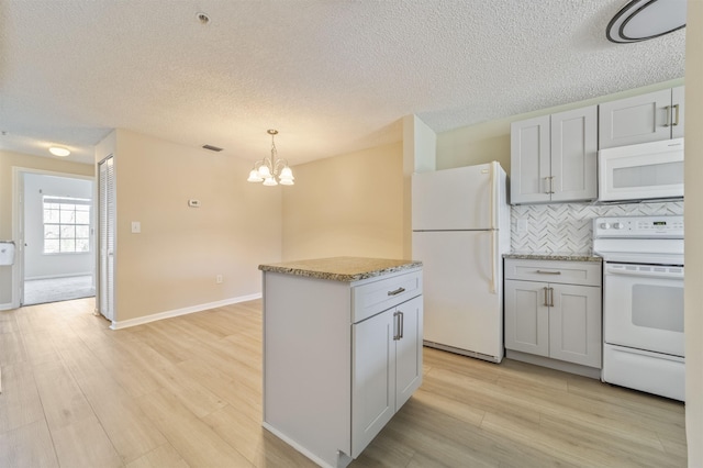 kitchen with a center island, gray cabinets, light wood-style flooring, backsplash, and white appliances