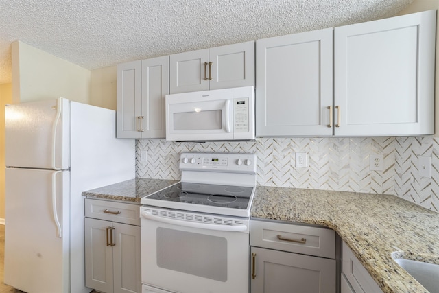 kitchen with a textured ceiling, light stone counters, white appliances, gray cabinets, and decorative backsplash