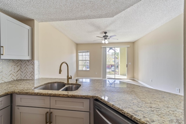 kitchen with tasteful backsplash, a sink, a peninsula, and light stone countertops