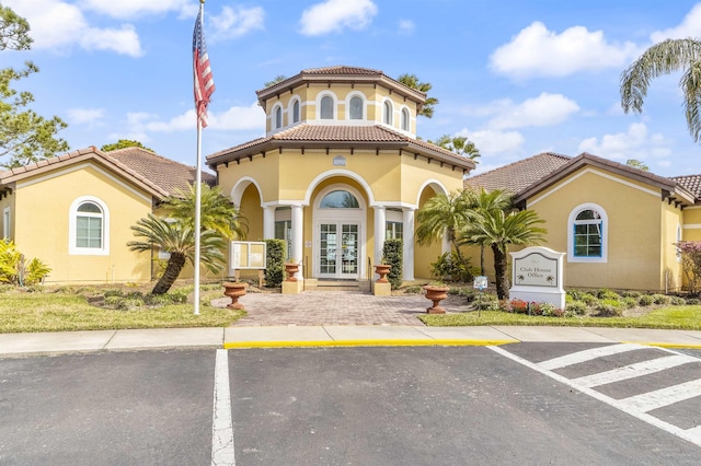 mediterranean / spanish house with stucco siding, a tiled roof, and french doors