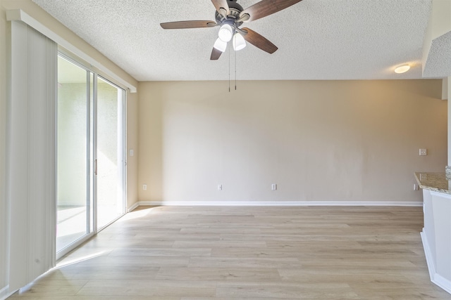 empty room featuring a healthy amount of sunlight, light wood finished floors, baseboards, and a textured ceiling