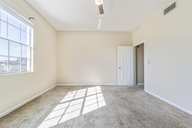 unfurnished room with visible vents, carpet flooring, ceiling fan, a textured ceiling, and baseboards