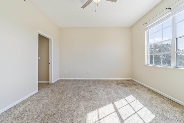 carpeted empty room featuring ceiling fan and baseboards