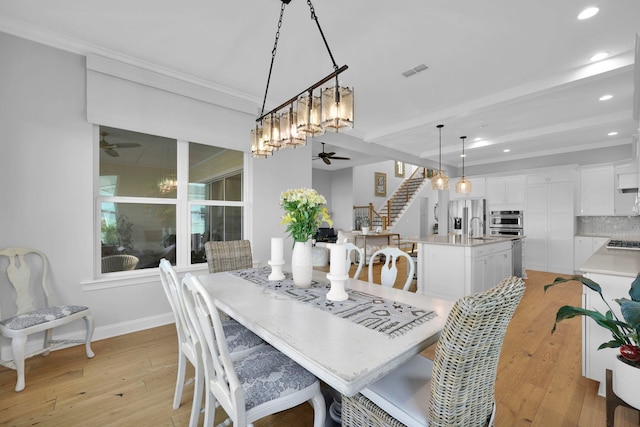 dining space with beamed ceiling, light hardwood / wood-style floors, sink, ceiling fan, and crown molding