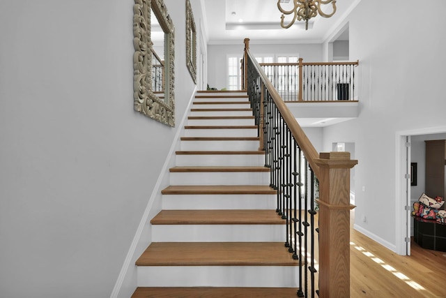 stairway with hardwood / wood-style flooring, ornamental molding, and an inviting chandelier