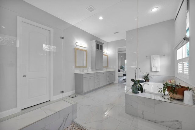 bathroom featuring vanity and a relaxing tiled tub