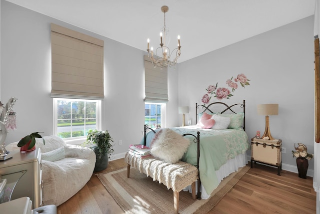 bedroom featuring wood-type flooring, a high ceiling, and a chandelier