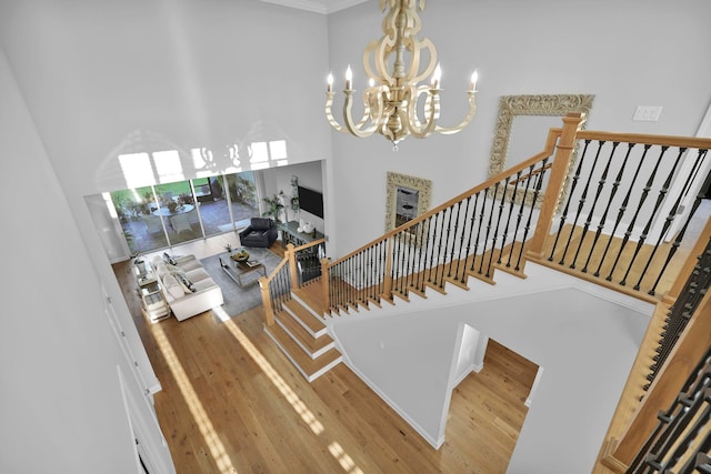 stairway with a notable chandelier, a towering ceiling, and hardwood / wood-style flooring