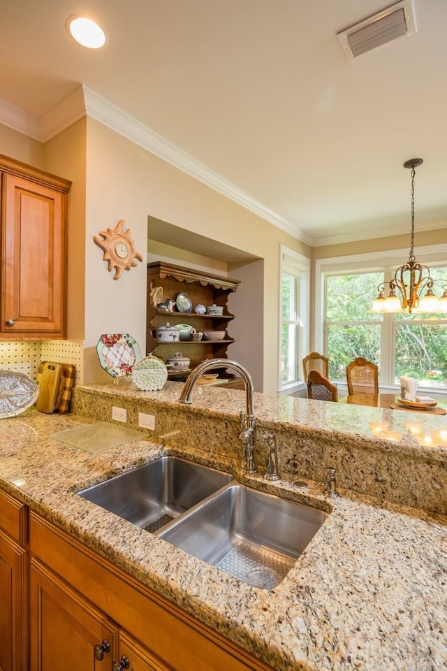 485 Ocean Forest Dr, Saint Augustine, FL 32080 - kitchen featuring visible vents, crown molding, light stone countertops, a sink, and brown cabinetry