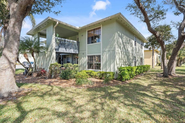 back of property featuring a balcony and a lawn