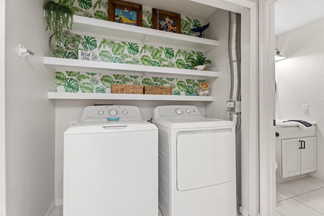 clothes washing area featuring laundry area, light tile patterned flooring, and washer and clothes dryer