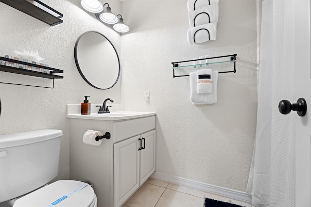 bathroom featuring baseboards, toilet, a textured wall, tile patterned floors, and vanity