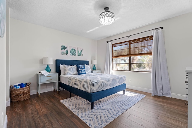 bedroom with a textured ceiling, baseboards, and wood finished floors