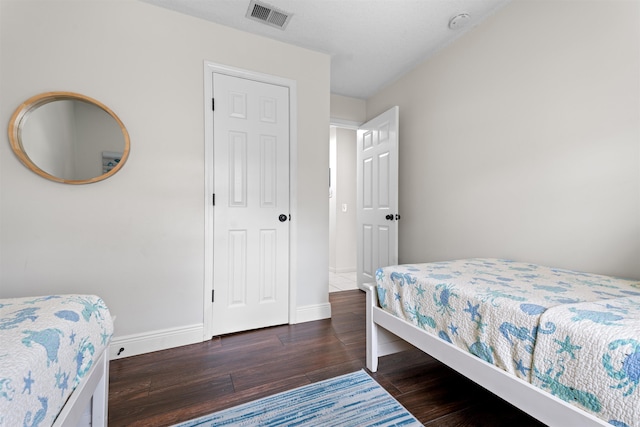 bedroom with dark wood-style floors, visible vents, and baseboards