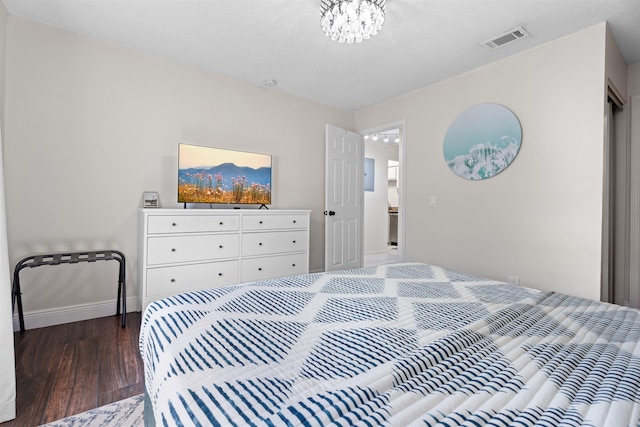 bedroom featuring visible vents, an inviting chandelier, baseboards, and wood finished floors