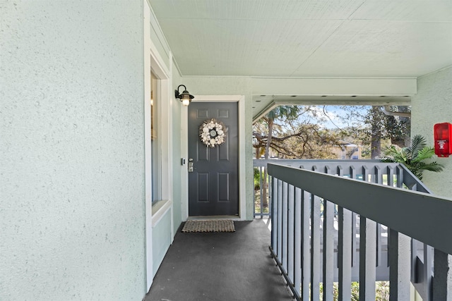 view of exterior entry with stucco siding and a balcony