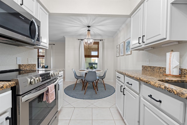 kitchen with light stone counters, light tile patterned floors, ornamental molding, white cabinets, and appliances with stainless steel finishes