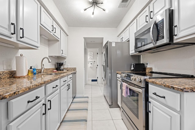 kitchen with visible vents, appliances with stainless steel finishes, light tile patterned flooring, white cabinetry, and a sink