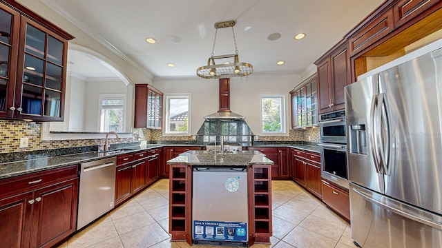 kitchen featuring decorative backsplash, stainless steel appliances, pendant lighting, dark stone countertops, and a center island