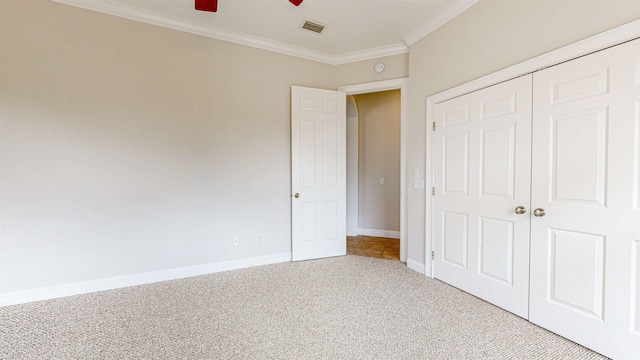 unfurnished bedroom with carpet, ceiling fan, crown molding, and a closet