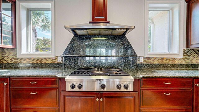 kitchen with backsplash, stainless steel gas cooktop, dark stone countertops, and exhaust hood