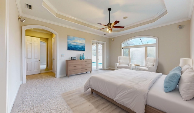 carpeted bedroom with a raised ceiling, ceiling fan, crown molding, and french doors