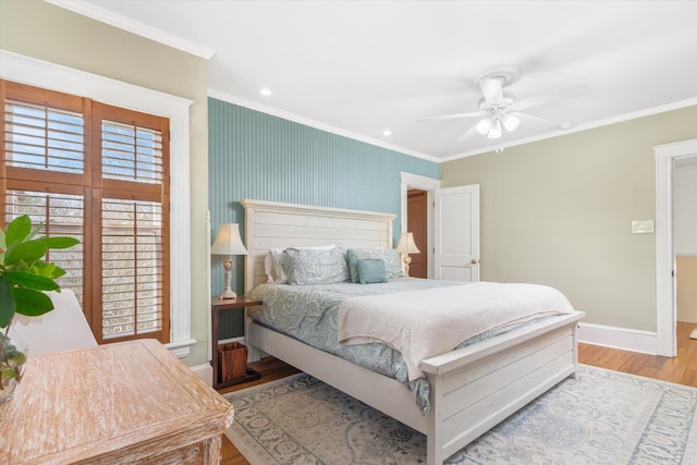 bedroom with crown molding, multiple windows, wood finished floors, and baseboards