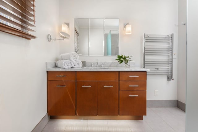 bathroom featuring vanity, radiator, baseboards, and tile patterned flooring