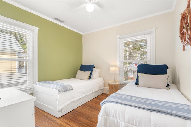 bedroom featuring crown molding, light wood-style flooring, visible vents, and ceiling fan