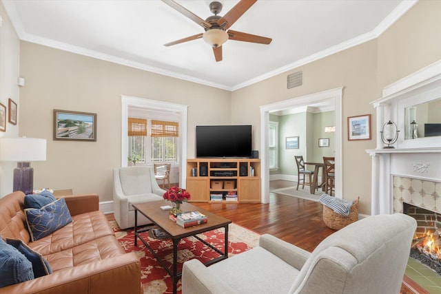 living room with wood finished floors, baseboards, visible vents, a tile fireplace, and ceiling fan