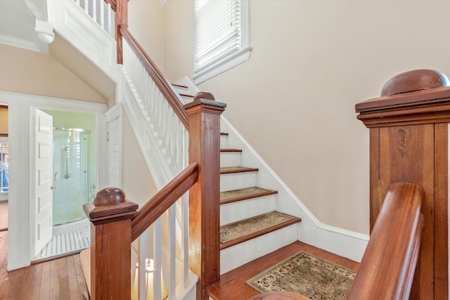 staircase with wood-type flooring and ornamental molding