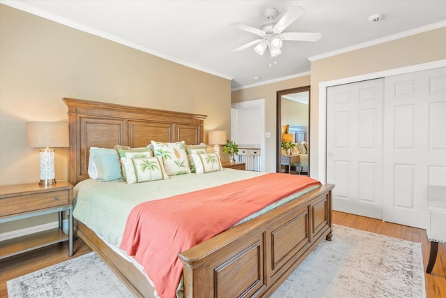 bedroom featuring crown molding, light wood-style flooring, a closet, and ceiling fan