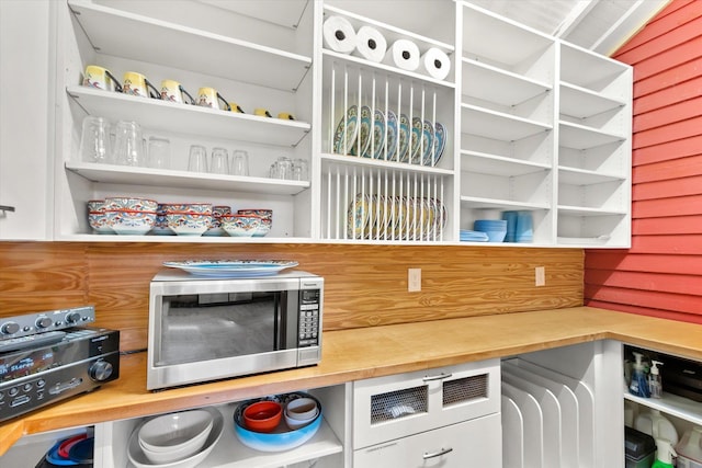 interior space featuring stainless steel microwave, open shelves, and wooden counters