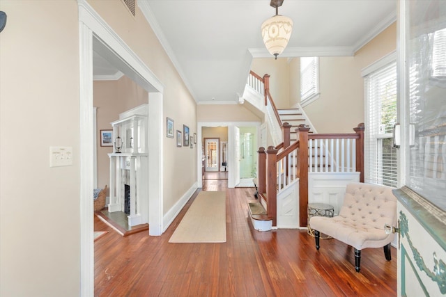 foyer featuring visible vents, ornamental molding, hardwood / wood-style flooring, stairway, and baseboards