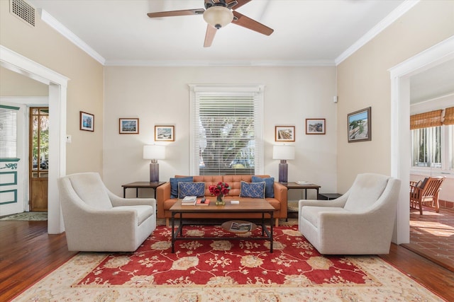 living room featuring visible vents, crown molding, a ceiling fan, and wood finished floors