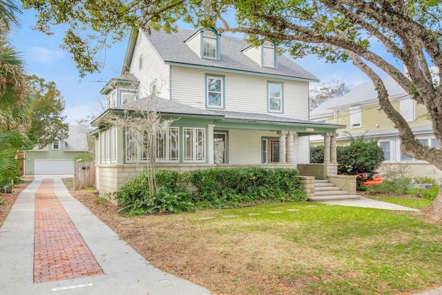 view of front of home with a front yard, covered porch, driveway, and a shingled roof