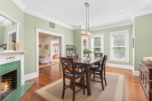 dining space featuring light wood-type flooring, baseboards, visible vents, and crown molding