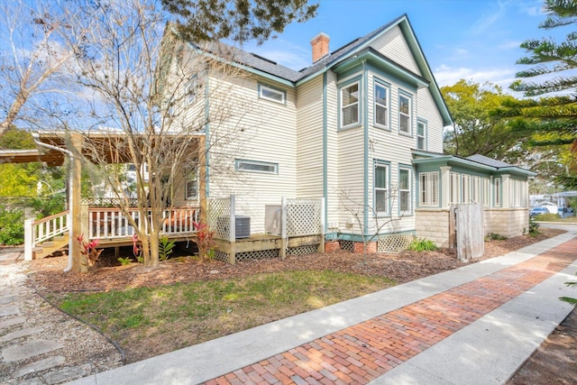 view of side of home featuring a wooden deck and a chimney