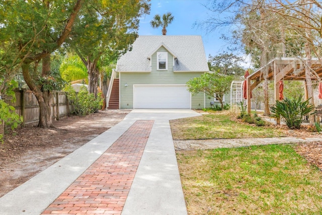 view of front facade featuring stairs, fence, a garage, and driveway