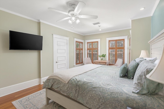 bedroom with visible vents, crown molding, baseboards, and wood finished floors